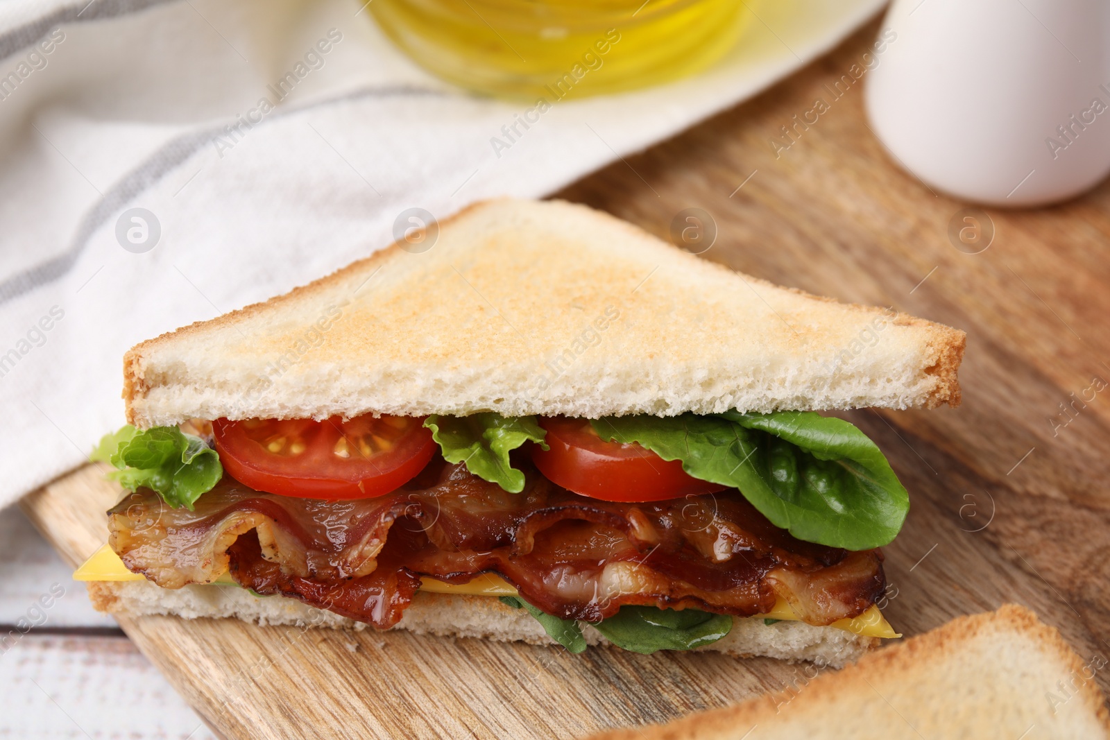 Photo of Delicious sandwich with fried bacon on wooden rustic table, closeup