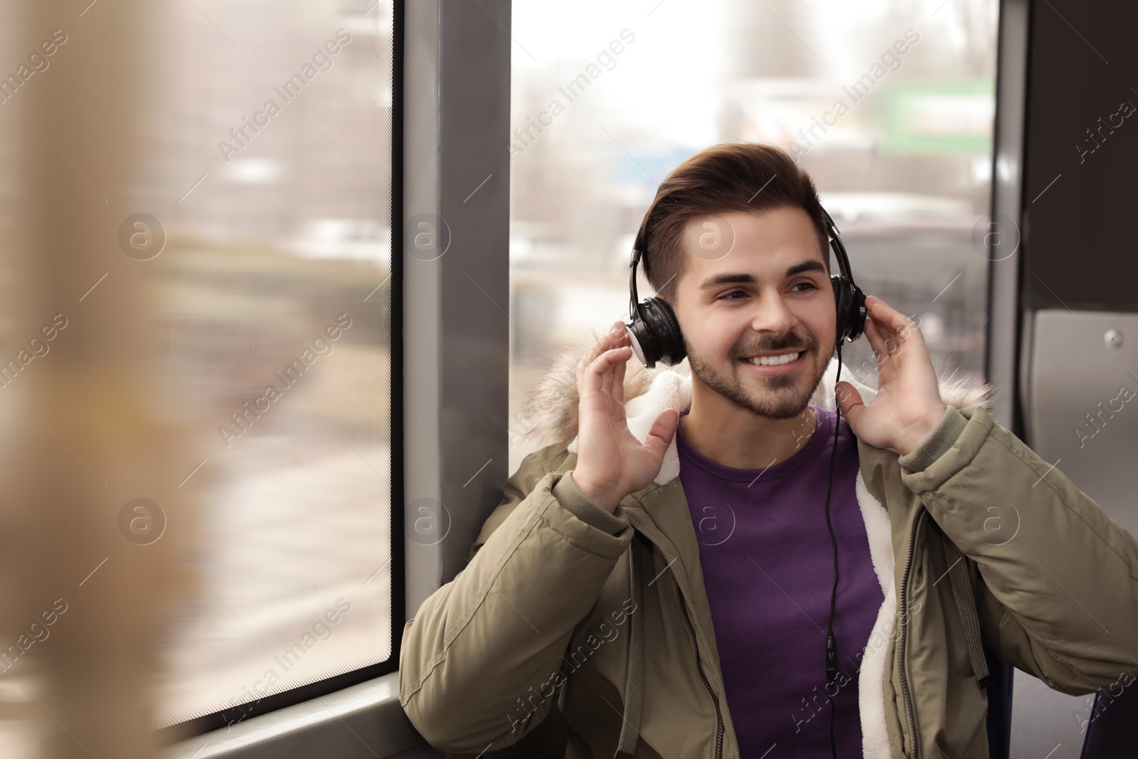 Photo of Young man listening to music with headphones in public transport