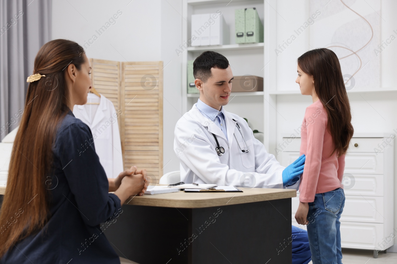 Photo of Gastroenterologist examining girl with stomach ache in clinic