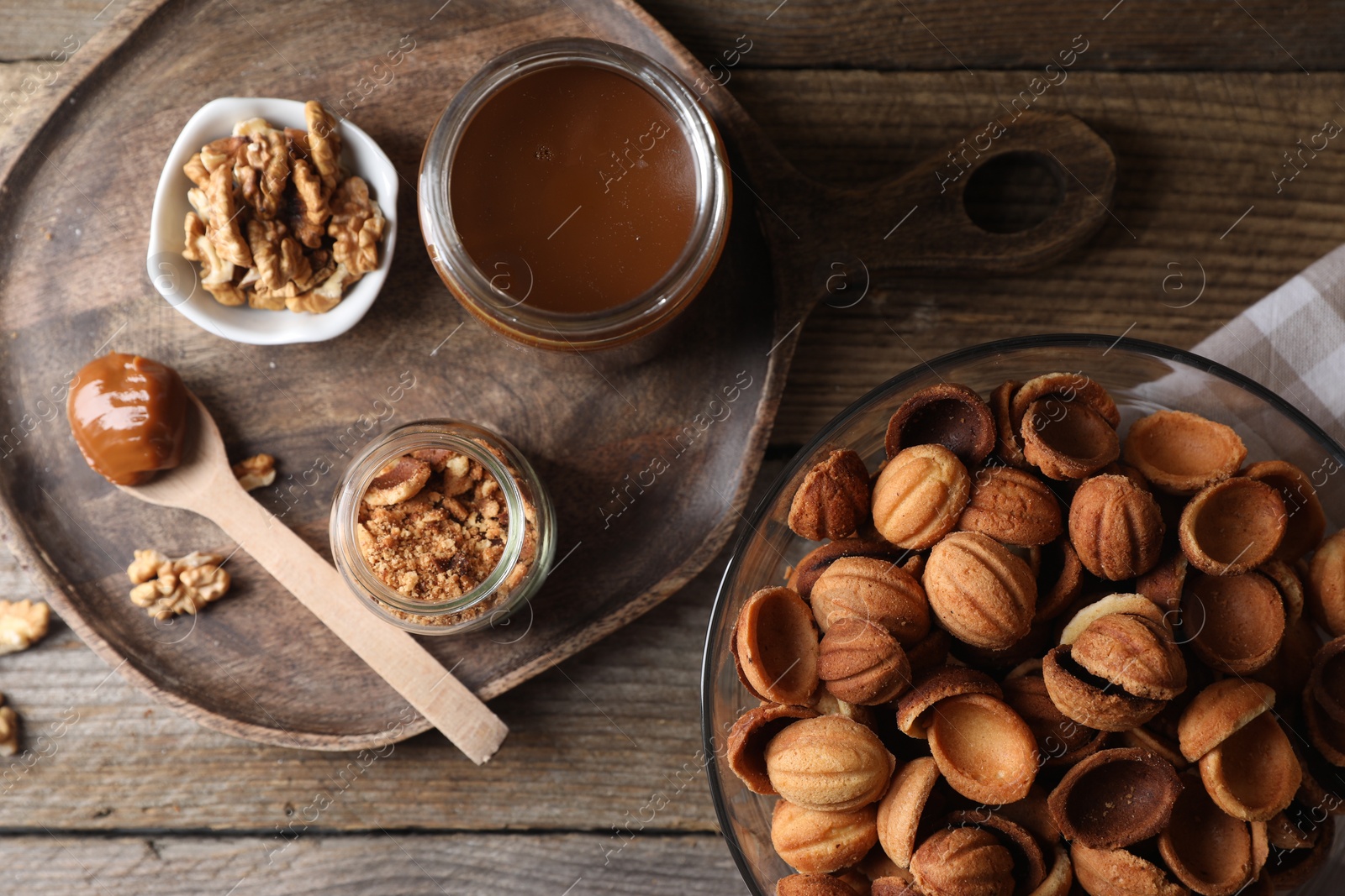 Photo of Making walnut shaped cookies. Cooked dough, caramelized condensed milk and nuts on wooden table, flat lay