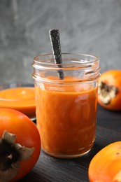 Photo of Delicious persimmon jam in glass jar served on dark gray wooden table