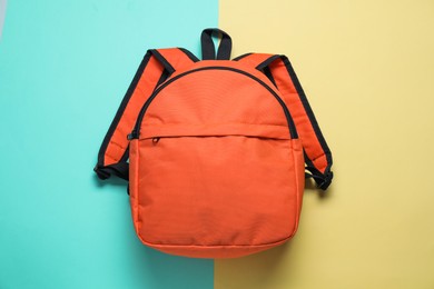 Photo of Stylish orange backpack on color background, top view