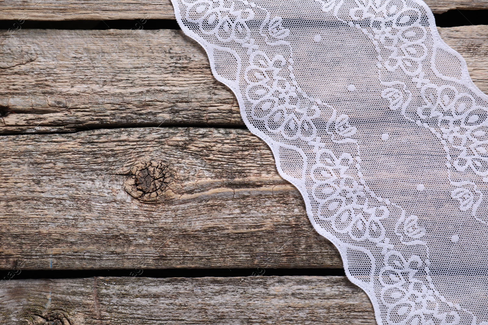 Photo of White lace on wooden table, top view. Space for text