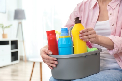 Photo of Woman with basin of detergents in living room, closeup. Cleaning service