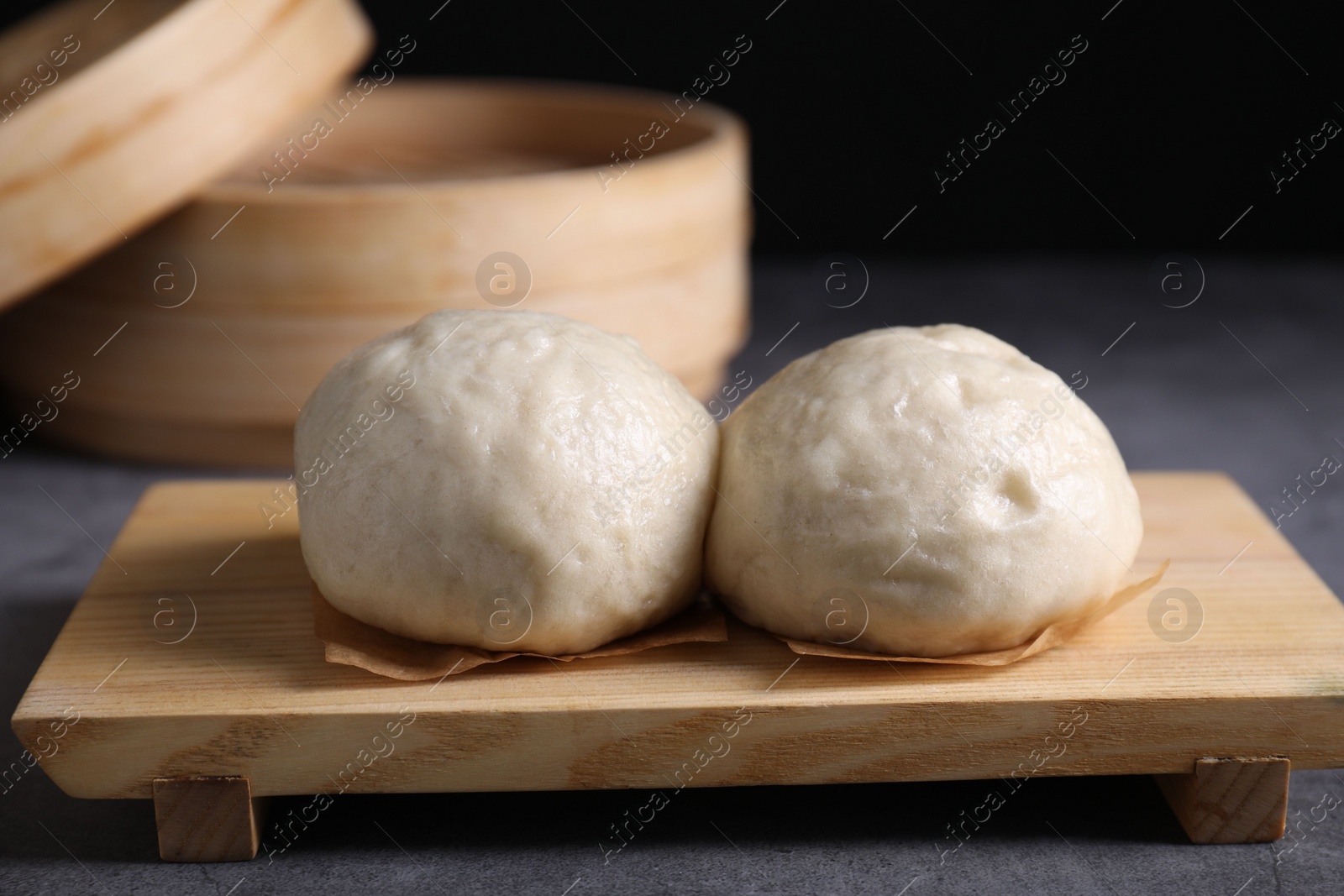 Photo of Delicious Chinese steamed buns on grey textured table, closeup