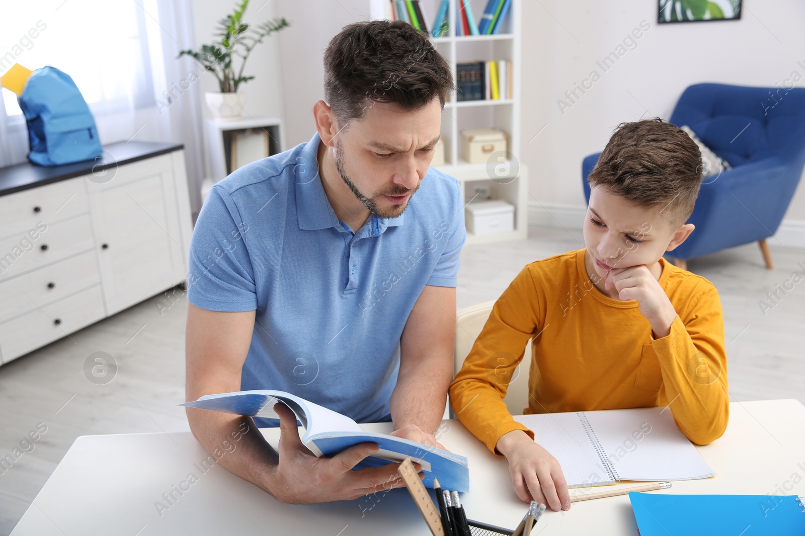 Photo of Dad helping his son with homework in room