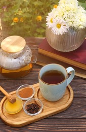 Photo of Tray with delicious tea and ingredients on wooden table