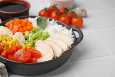 Delicious poke bowl with meat, egg, rice and vegetables on white tiled table, closeup. Space for text