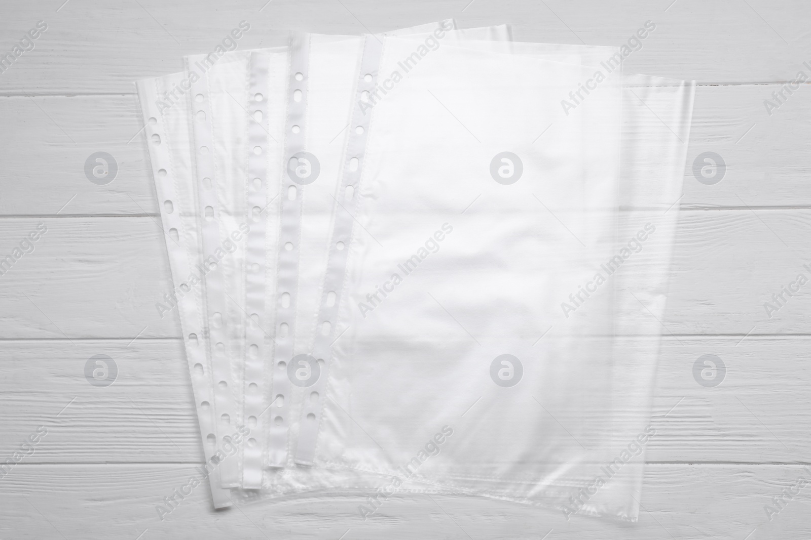 Photo of Punched pockets on white wooden table, flat lay