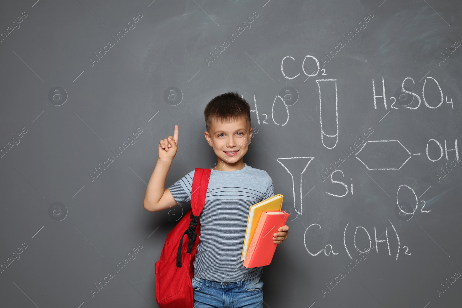 Photo of Little child with school supplies and chemical formulas on grey background