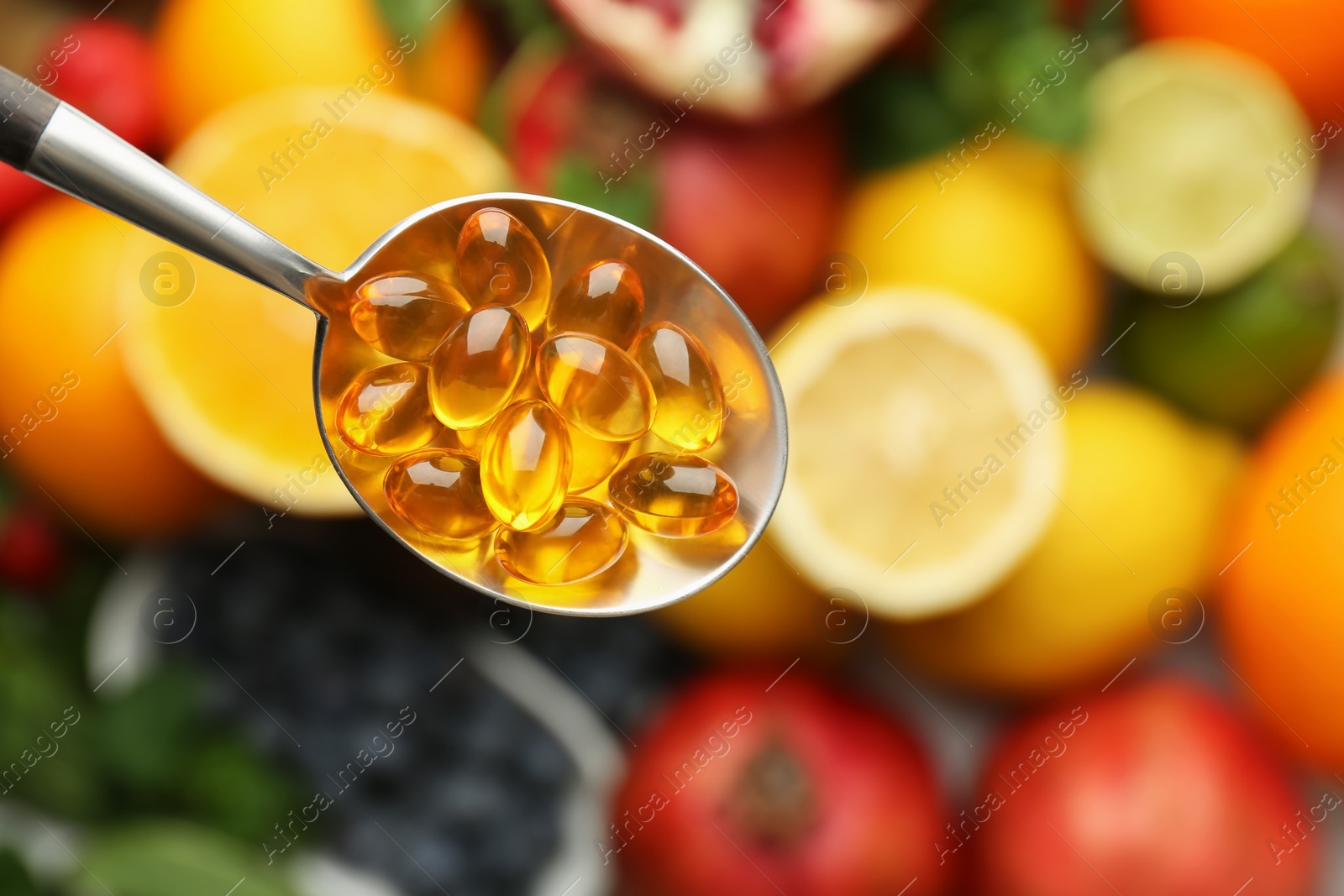 Photo of Vitamin pills in spoon over fresh fruits, top view. Space for text