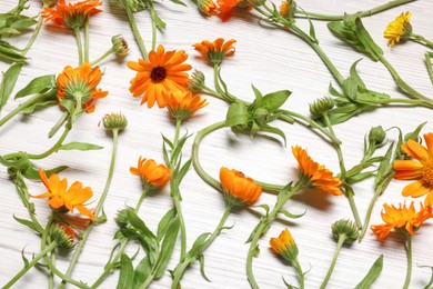 Photo of Beautiful calendula flowers on white wooden table, above view