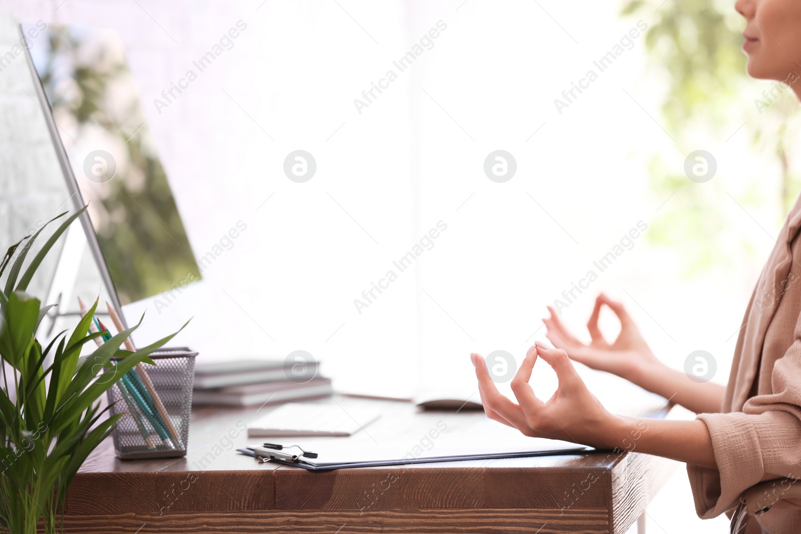 Photo of Businesswoman meditating at workplace, closeup with space for text. Zen concept