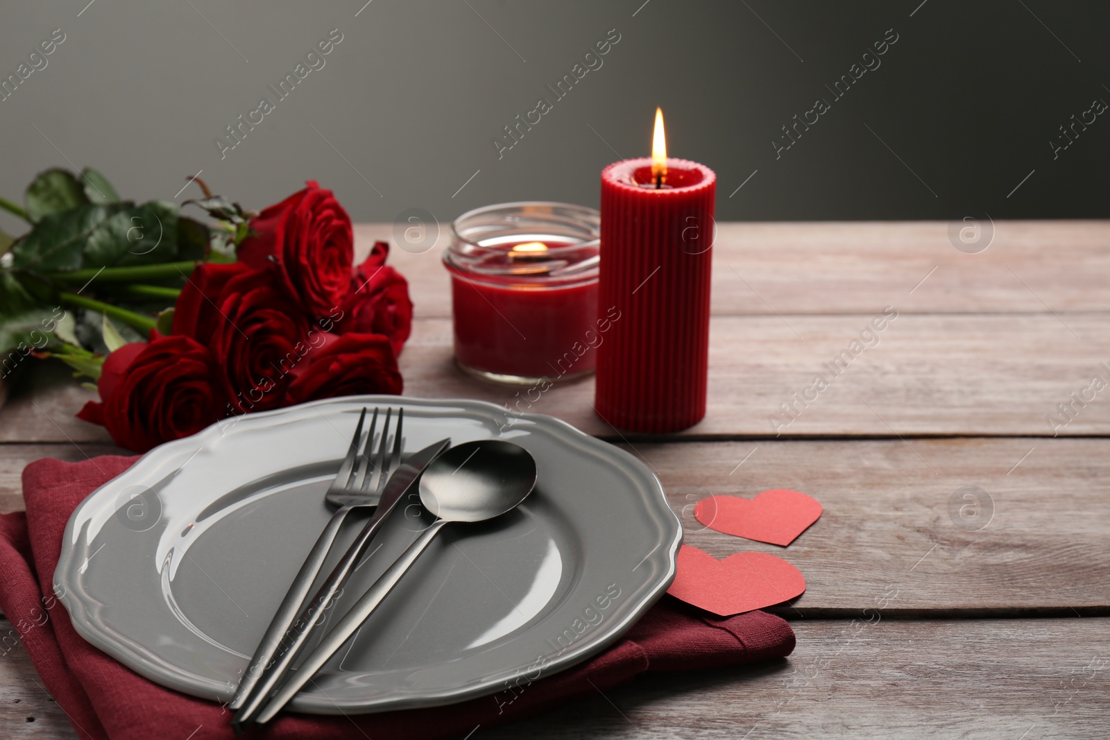 Photo of Romantic place setting with red roses, candles and decorative hearts on wooden table, space for text. St. Valentine's day dinner