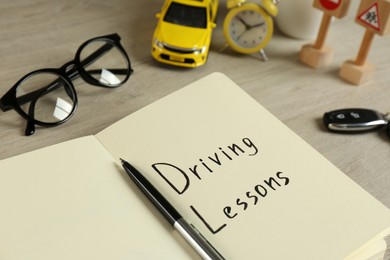 Workbook for driving lessons with pen on wooden table, closeup. Passing license exam