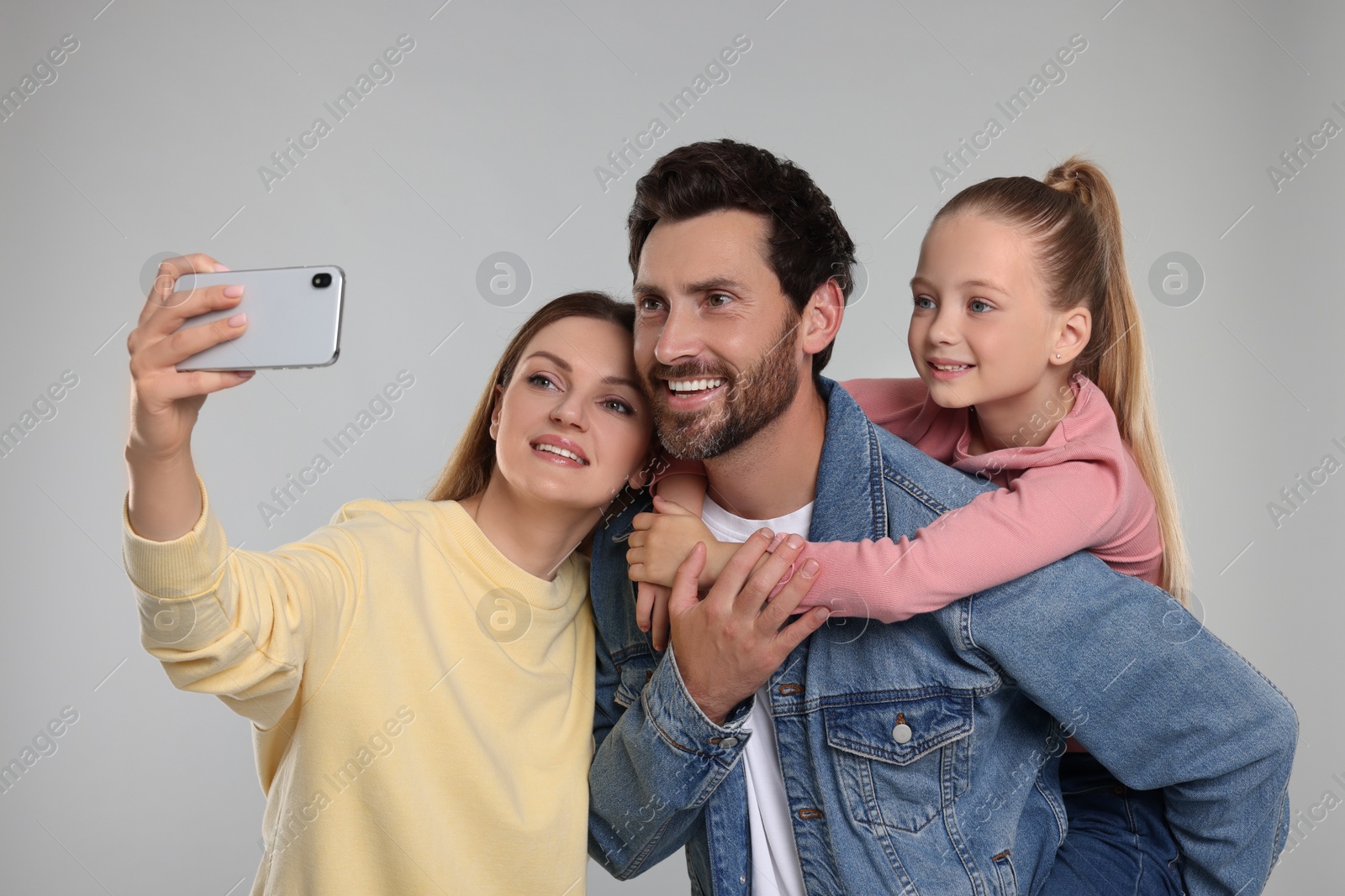 Photo of Happy family taking selfie on light grey background