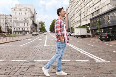 Photo of Young man crossing street. Traffic rules and regulations