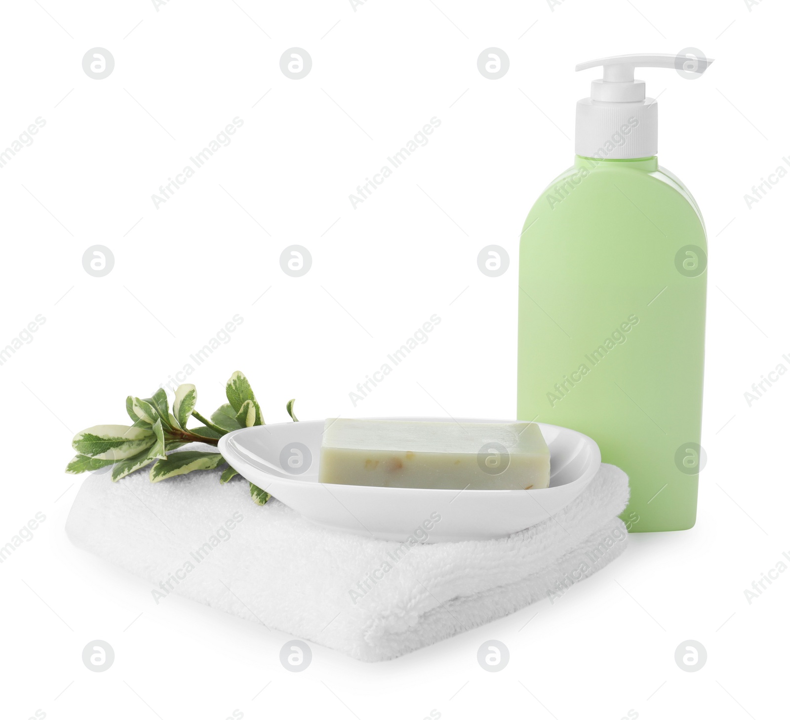 Photo of Dish with soap bar, dispenser and terry towel on white background