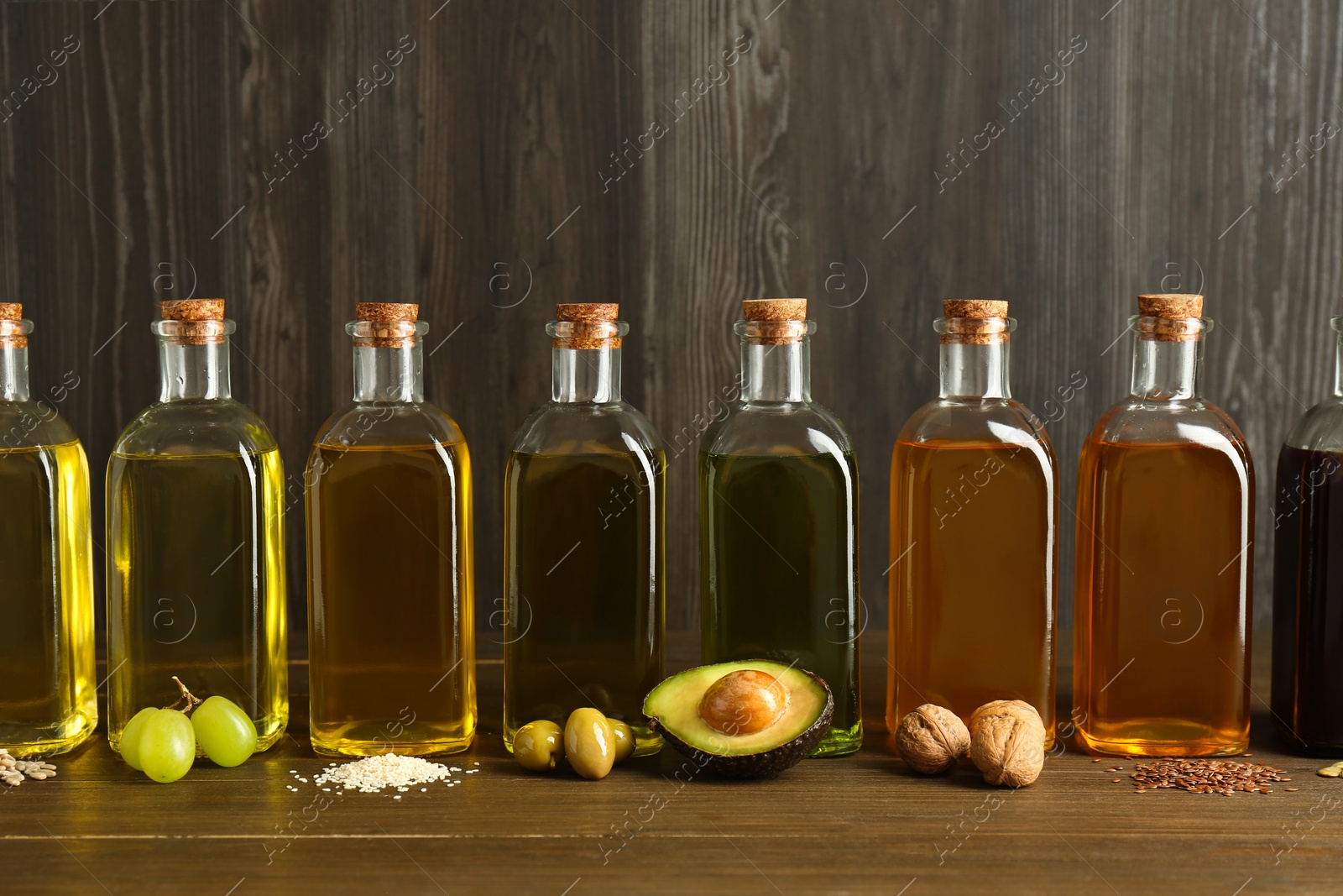 Photo of Vegetable fats. Different oils in glass bottles and ingredients on wooden table