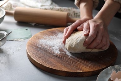 Photo of Woman kneading dough at grey table, closeup