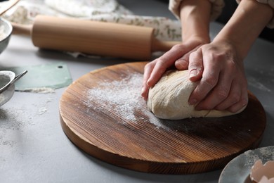 Woman kneading dough at grey table, closeup