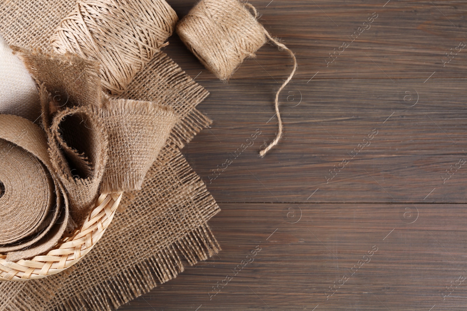 Photo of Pieces of burlap fabric and twine on wooden table, flat lay. Space for text