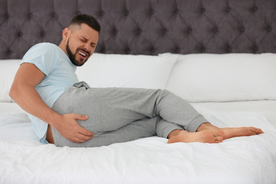 Photo of Man suffering from hemorrhoid on bed at home
