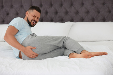 Man suffering from hemorrhoid on bed at home