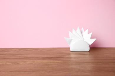 Photo of Napkin holder with paper serviettes on table against color background. Space for text