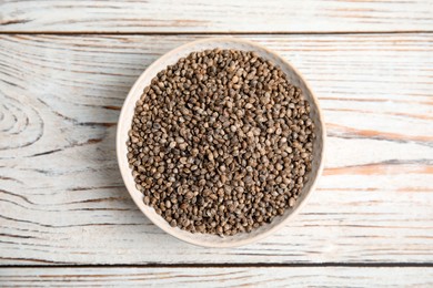 Photo of Bowl with organic hemp seeds on white wooden table, top view