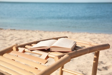 Book on wooden deck chair at seaside. Reading while vacation