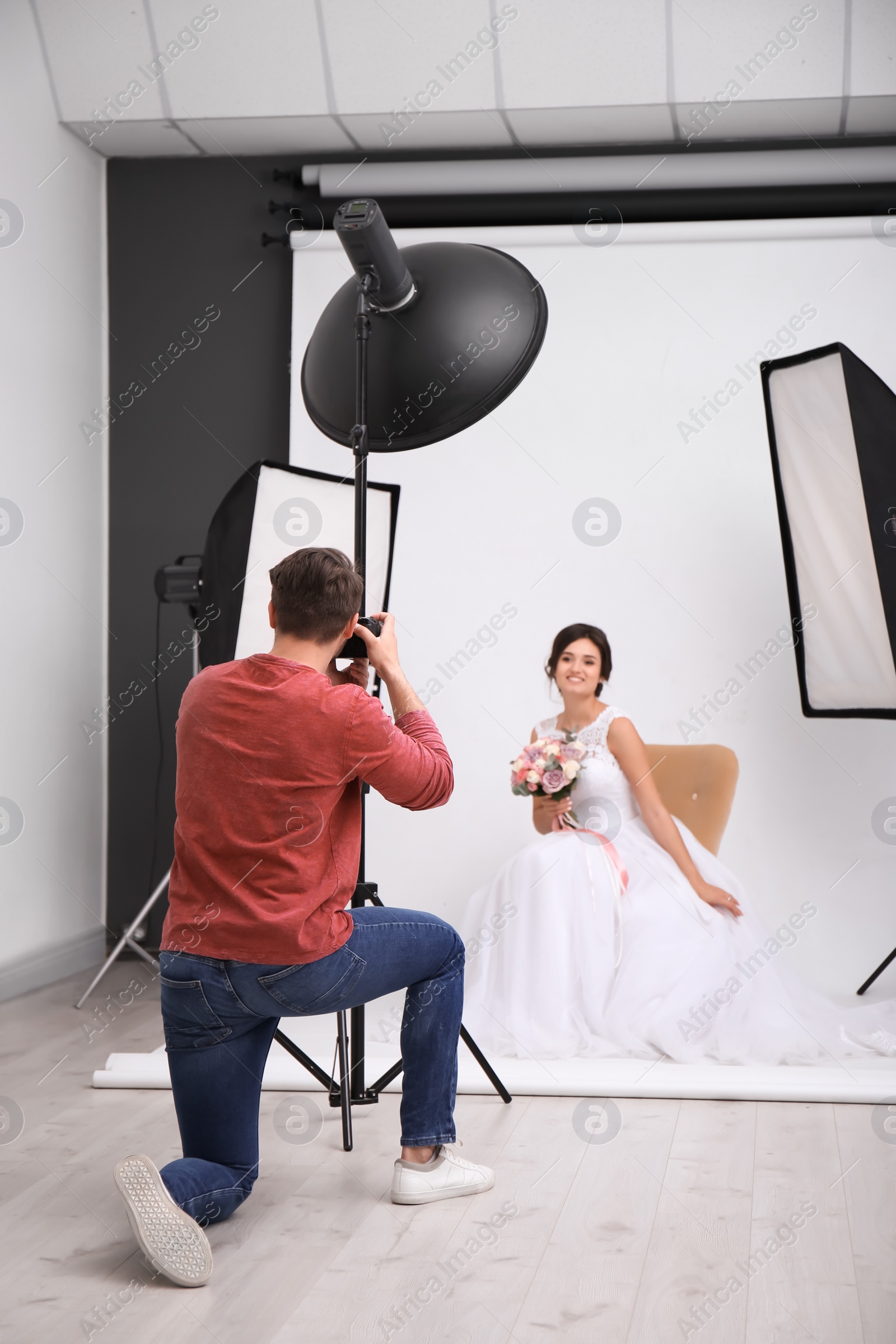 Photo of Professional photographer taking photo of beautiful bride in studio