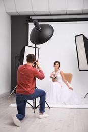 Photo of Professional photographer taking photo of beautiful bride in studio