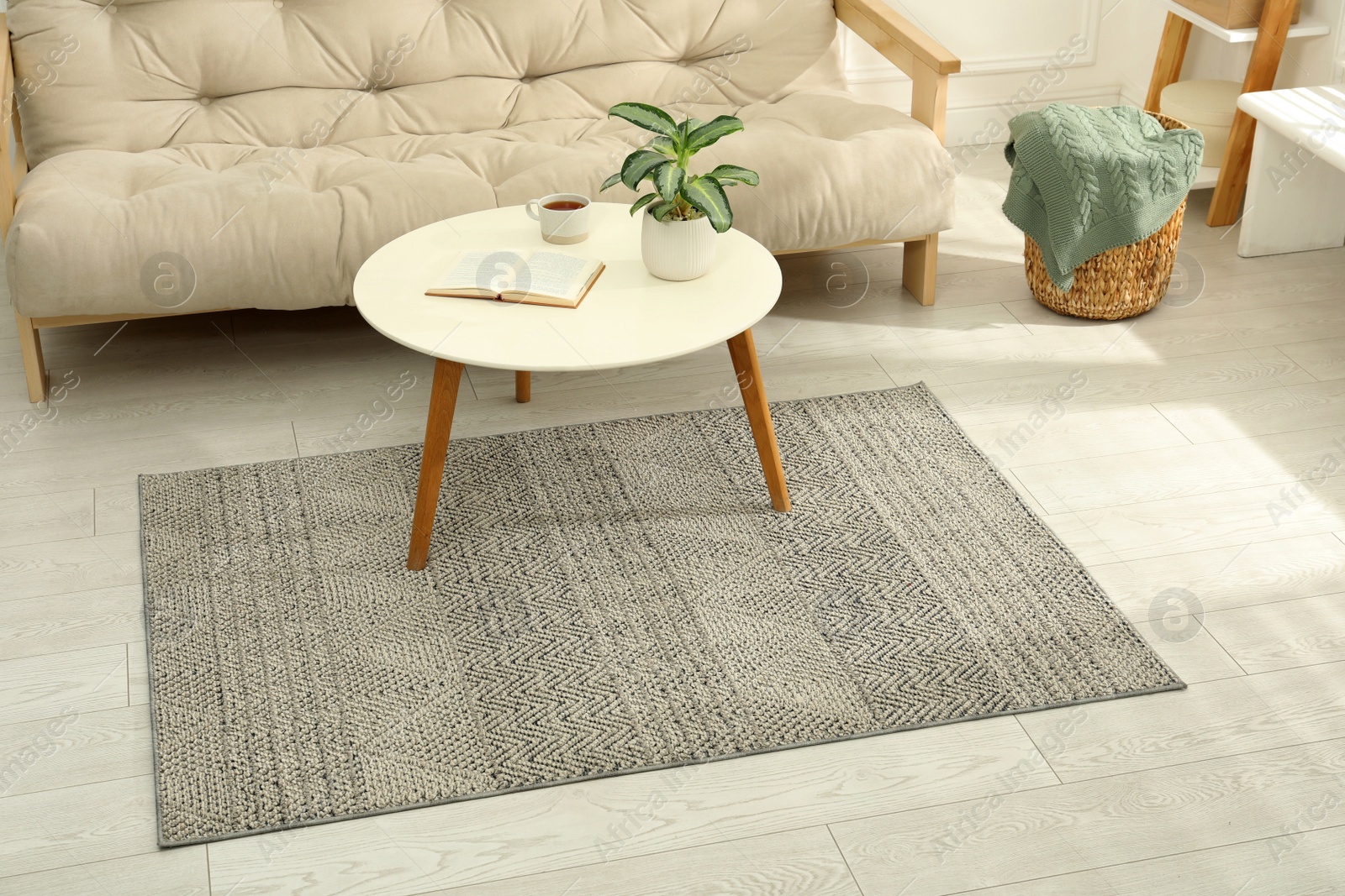 Photo of Stylish rug with pattern and table on floor in living room