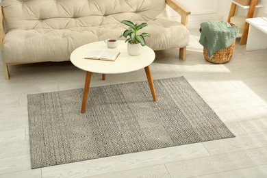 Photo of Stylish rug with pattern and table on floor in living room