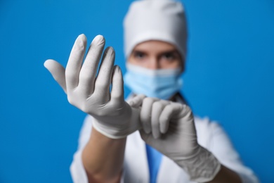 Photo of Doctor in medical gloves against blue background, focus on hands