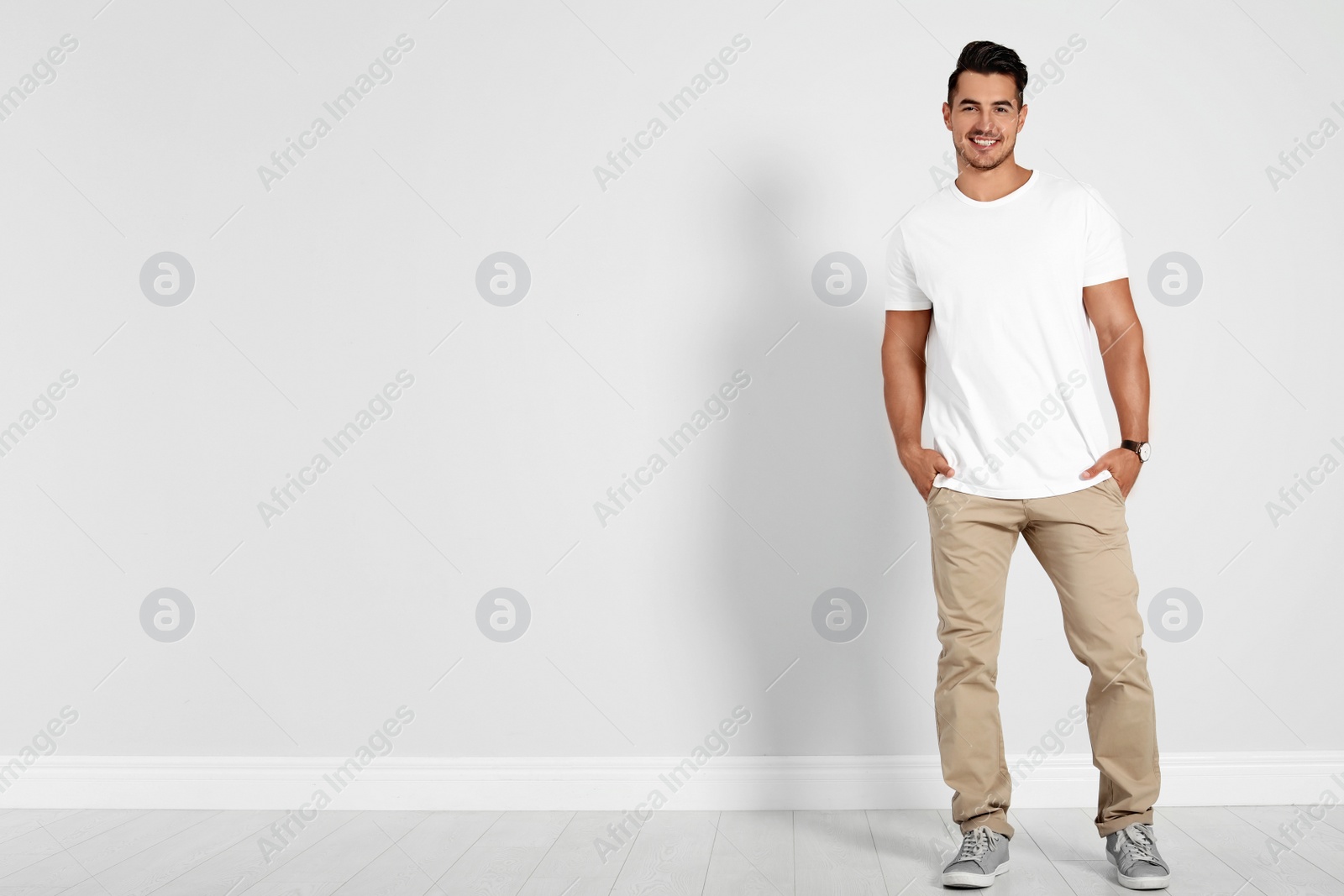 Photo of Full length portrait of handsome young man and space for text on white wall background