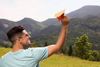 Photo of Man throwing paper plane in mountains on sunny day