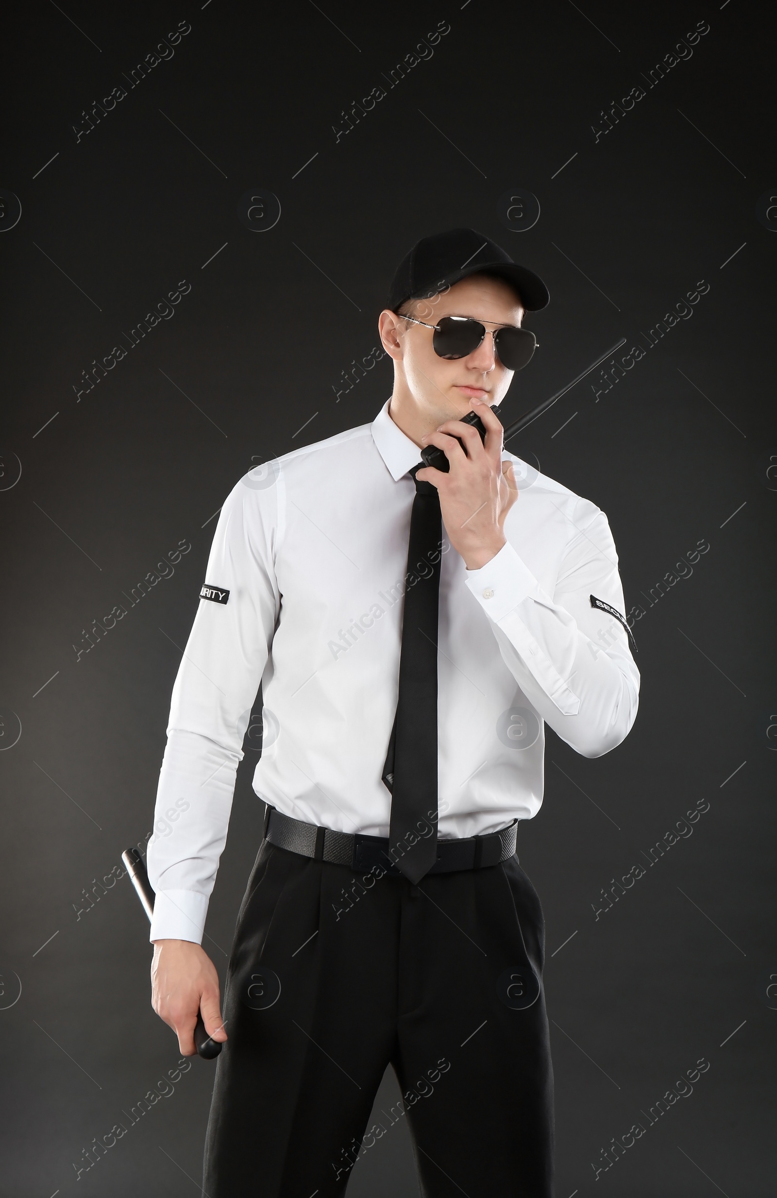 Photo of Male security guard using portable radio transmitter on dark background