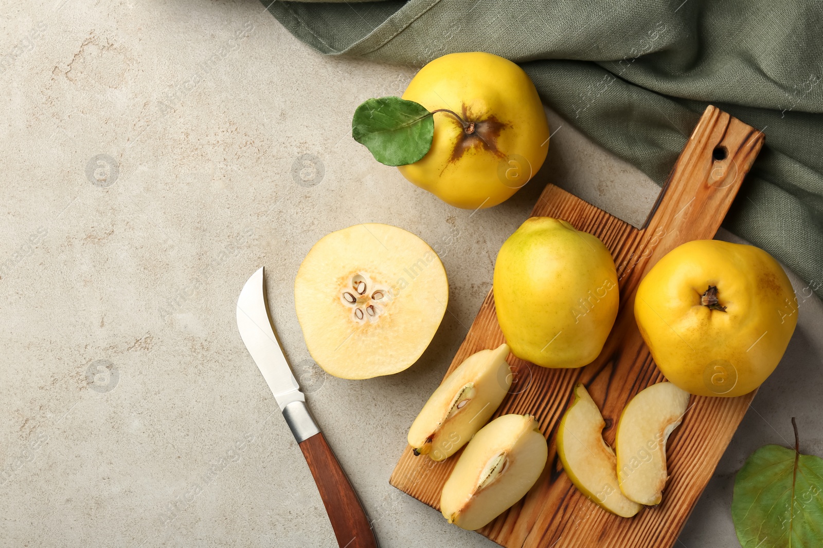 Photo of Tasty ripe quince fruits and knife on grey table, flat lay. Space for text