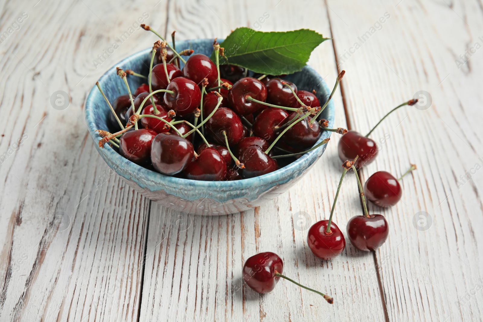 Photo of Bowl with sweet red cherries on wooden table