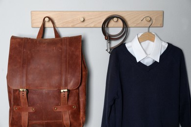 Photo of Shirt, jumper and bag hanging on white wall. School uniform