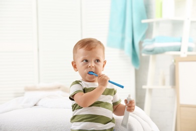 Cute little boy with toothbrush on blurred background