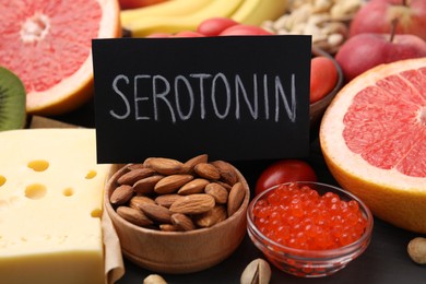 Photo of Many different products and card with word Serotonin on table, closeup. Natural antidepressants