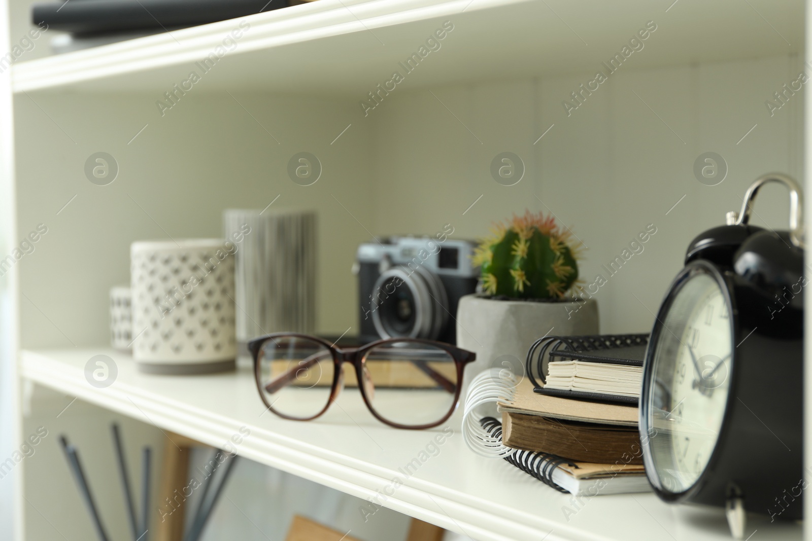 Photo of White shelving unit with glasses and different decorative elements