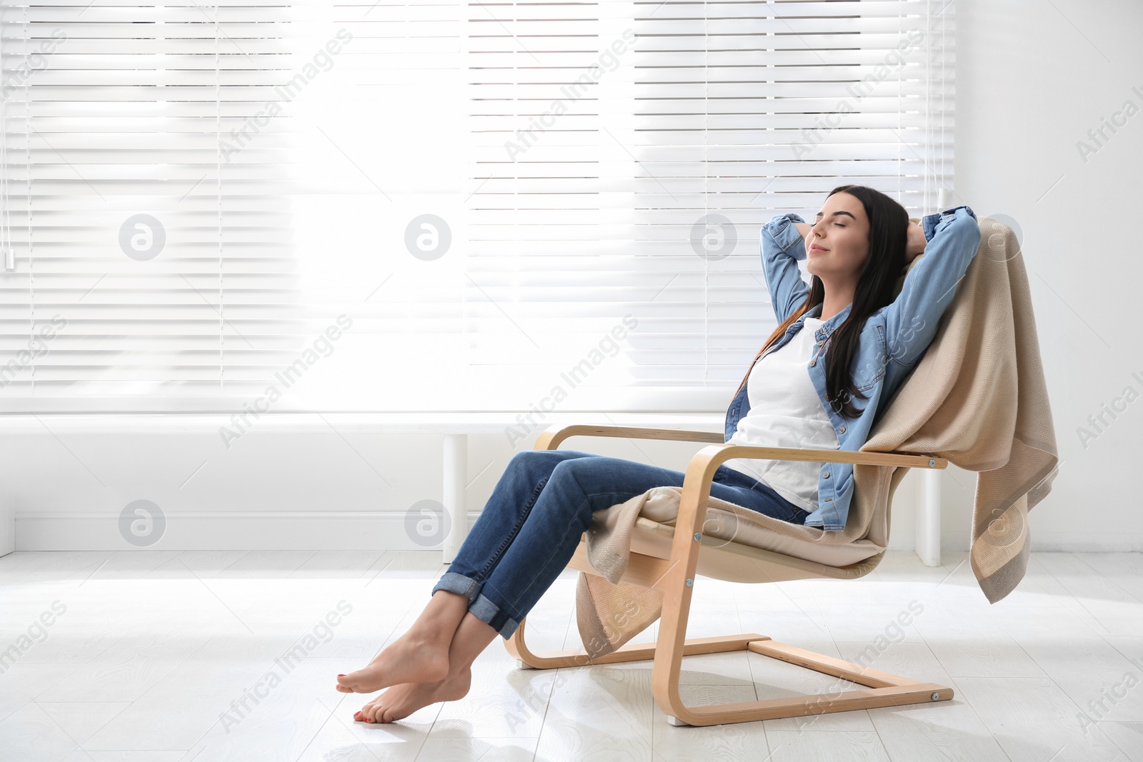 Photo of Young woman relaxing in armchair near window at home