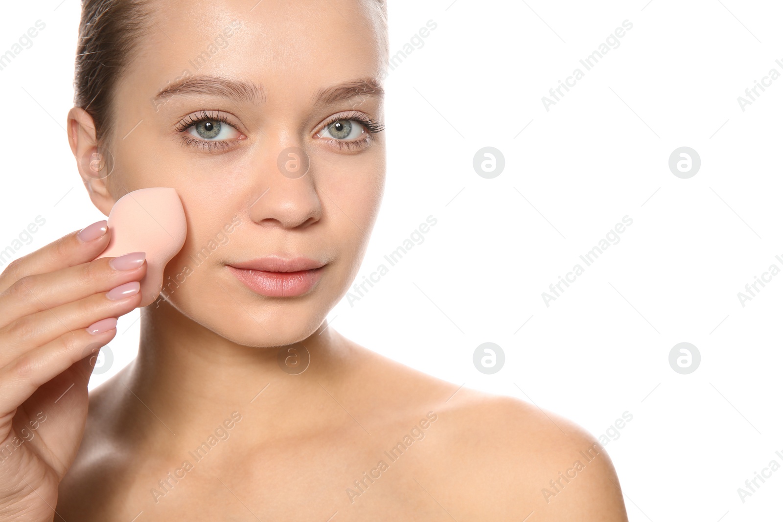 Photo of Young woman applying foundation on her face against white background