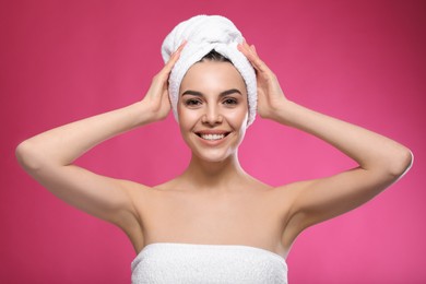 Happy young woman with towel on head against pink background. Washing hair