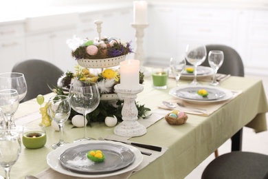 Beautiful Easter table setting with burning candles indoors