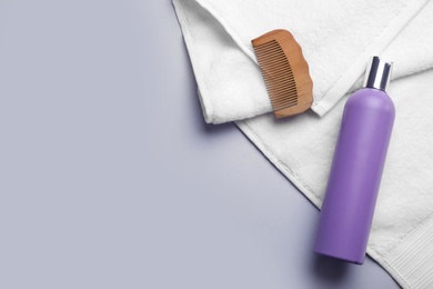 Photo of Bottle of shampoo, towel and comb on color background, top view with space for text